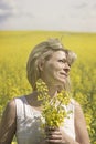 Beautiful dreamy woman in a rapeseed field with a bouquet dreams and enjoys nature. Royalty Free Stock Photo