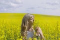 Beautiful dreamy woman in a rapeseed field with a bouquet dreams and enjoys nature. Royalty Free Stock Photo