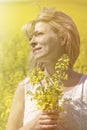 Beautiful dreamy woman in a rapeseed field with a bouquet dreams and enjoys nature. Royalty Free Stock Photo