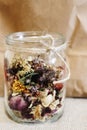 Beautiful dried flowers, different flavors, in glass jar on rust Royalty Free Stock Photo