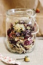 Beautiful dried flowers, different flavors, in glass jar on rust Royalty Free Stock Photo