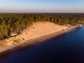 Beautiful drone areal photography view of large dune and pine forest near river Lielupe. Photo taken on sunset, Europe, Latvia