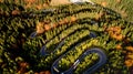 Beautiful drone view of winding forest road in the middle of mountains. Colourful landscape with rural road, trees with yellow lea Royalty Free Stock Photo