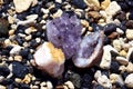 A beautiful druse and geode of amethyst and druse of citrine lie on wet stones on the seashore. Crystals of semi-precious stones Royalty Free Stock Photo