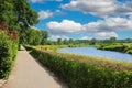 Beautiful dutch countryside landscape, empty riverside cycling hiking path, green hedges, river Maas, forest, blue summer sky -