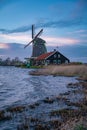 Beautiful Dutch landscape of Zaanse Schans village. Ancient windmills at the water\'s edge against a blue sky at dusk Royalty Free Stock Photo