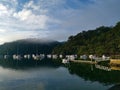 Beautiful early morning view of a creek with reflections of blue sky, boats, foggy mountains and trees on water Royalty Free Stock Photo