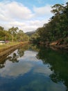 Beautiful early morning view of a creek with reflections of blue sky, foggy mountains and trees on water Royalty Free Stock Photo