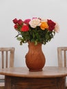 Beautiful earthenware vase of fresh red and pink roses on wooden table Royalty Free Stock Photo