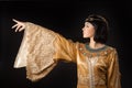 Beautiful Egyptian woman like Cleopatra pointing finger away on black background