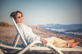 Beautiful elderly woman sitting in a deckchair on the beach and Royalty Free Stock Photo