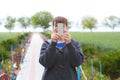 Beautiful elderly woman taking picture with phone. Alley with blooming flowers on background. Royalty Free Stock Photo