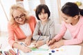 Beautiful elderly woman teaches children to draw. Little children draw. Drawing lessons.