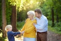 Beautiful eldery woman and her adult son, and her little grandson tenderly embracing together in park