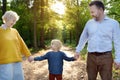 Beautiful eldery woman and her adult son, and her little grandson walking together in sunny summer park Royalty Free Stock Photo