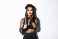 Beautiful and elegant asian woman in gothic lace dress celebrating halloween, dress-up as witch, sending air kiss at