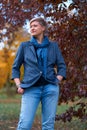 Beautiful elegant blond woman posing in autumn city park, dressed in blue jeans and jacket Royalty Free Stock Photo