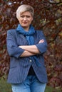 Beautiful elegant blond woman posing in autumn city park, dressed in blue jeans and jacket Royalty Free Stock Photo