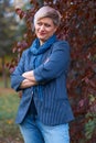 Beautiful elegant blond woman posing in autumn city park, dressed in blue jeans and jacket Royalty Free Stock Photo