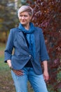 Beautiful elegant blond woman posing in autumn city park, dressed in blue jeans and jacket Royalty Free Stock Photo