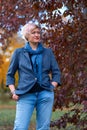 Beautiful elegant blond woman posing in autumn city park, dressed in blue jeans and jacket Royalty Free Stock Photo