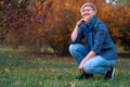 Beautiful elegant blond woman posing in autumn city park, dressed in blue jeans and jacket Royalty Free Stock Photo