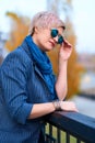 Beautiful elegant blond woman posing in autumn city park, dressed in blue jeans and jacket Royalty Free Stock Photo