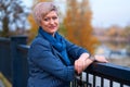 Beautiful elegant blond woman posing in autumn city park, dressed in blue jeans and jacket Royalty Free Stock Photo