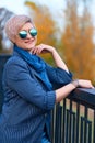 Beautiful elegant blond woman posing in autumn city park, dressed in blue jeans and jacket Royalty Free Stock Photo