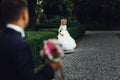 Beautiful elegant blonde bride running towards charming groom outdoors in park Royalty Free Stock Photo