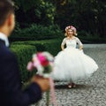 Beautiful elegant blonde bride running towards charming groom outdoors in park Royalty Free Stock Photo