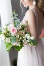 Beautiful elegant bouquet of roses and greenery in the gentle hands of the beautiful bride girl in a pink dress the air