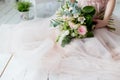 Beautiful elegant bouquet of roses and greenery in the gentle hands of the beautiful bride girl in a pink dress the air