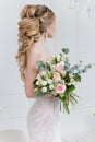 Beautiful elegant bouquet of roses and greenery in the gentle hands of the beautiful bride girl in a pink dress the air