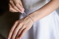 Beautiful elegant bride puts jewelry bracelet on her hand with pearls, close-up.Concept of preparing bride for wedding Royalty Free Stock Photo