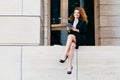 Beautiful elegant businesswoman in formal clothes and high-heeled shoes, having wavy hair and slender legs, using modern tablet fo Royalty Free Stock Photo