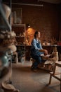 Beautiful elegant Caucasian ceramicist wearing apron shaping earthenware product in pottery workshop