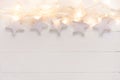 Beautiful elegant Christmas New Year background. White stars sparkling golden lights garland on plank wood. Upper border