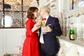 Beautiful elegant couple kisses and holds glasses of champagne in their hands against the background of New Year`s lights in a Royalty Free Stock Photo
