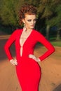 Beautiful elegant girl with beautiful makeup and hair in a red evening dress in the Park Royalty Free Stock Photo