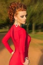 Beautiful elegant girl with beautiful makeup and hair in a red evening dress in the Park Royalty Free Stock Photo
