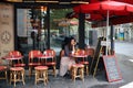 Beautiful elegant girl in Paris sits in a Parisian cafe and drinks coffee with a croissant