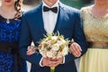 Beautiful elegant groom holding fabulous bouquet with bridesmaid