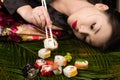 Beautiful elegant Korean girl lying on table and eating rolls Royalty Free Stock Photo