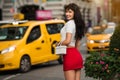 Beautiful elegant smiling woman walking to yellow taxi on city street of New York.