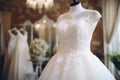 Beautiful elegant wedding dress on mannequin in bridal shop boutique salon. Interior of luxury wedding shop with bridal