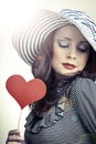 Beautiful elegant woman in hat holding heart in her hands and sm
