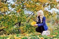 Beautiful elegant woman sitting with leafs in a park in autumn Royalty Free Stock Photo