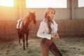 Beautiful elegant young blonde girl standing near her horse dressing uniform competition Royalty Free Stock Photo