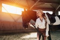 Beautiful elegant young blonde girl standing near her horse dressing uniform competition Royalty Free Stock Photo